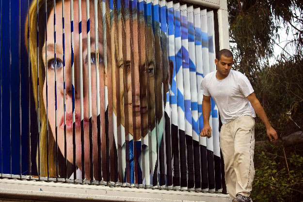 Cipi Livni izraeli külügyminiszter, a legnagyobb kormánypárt, a centrista Kadima párt elnöke (b) és Benjámin Netanjahu, a jobboldali Likud párt elnöke láthatók a tartalmát automatikusan átváltó választási hirdetőtáblán