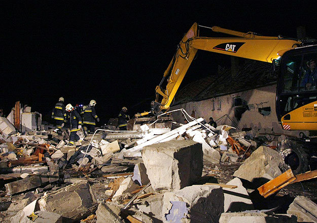 Tűzoltók munkagépekkel dolgoznak a romok között a polgári robbanás helyszínén