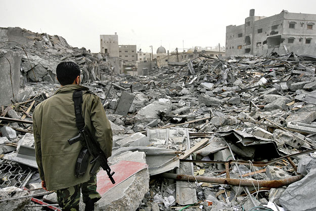 Fegyveres a lerombolt Hamász főhadiszállás előtt Gázában