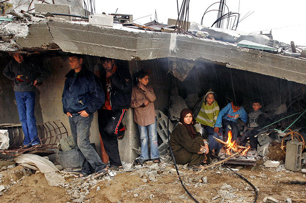 Palesztinok melegednek házuk romjai alatt a Gázai övezet északi részén fekvő Dzsabalija településen.