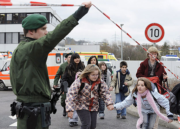 Rendõr felemeli a kordont szalagját, hogy gyerekek távozhassanak az Albertville Reáliskolából 2009. március 11-én, miután egy fekete harci öltözéket viselõ férfi behatolt a középiskolába és lõfegyverével tüzelni kezdett. 