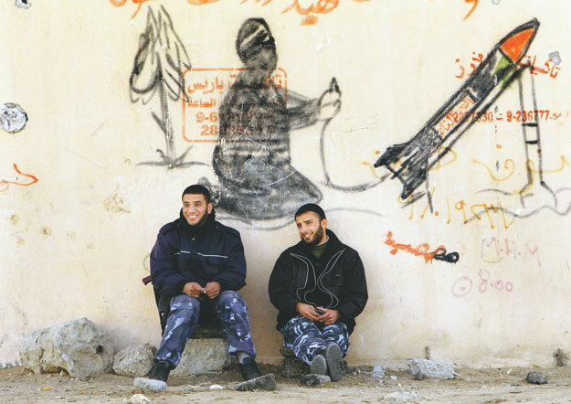 Hamasz-fegyveresek üldögélnek Gázában egy Izrael-ellenes graffiti tövében