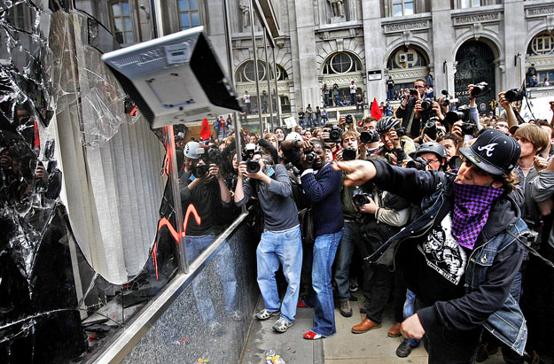 Anarchista tüntető dob be egy monitort a Royal Bank of Scotland épületének ablakán - a fotósok örömére is