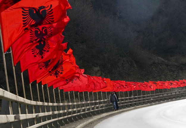 Albán nemzeti zászlókkal feldíszített hídon mennek koszovóiak a koszovói Kacanikban 2009. február 16-án, a koszovói függetlenség első évfordulója előtt