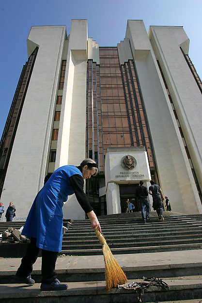 Törmelékeket, seper össze egy takarítónő a kommunisták elsöprő választási győzelme ellen tiltakozó kormányellenes tüntetők által megrongált elnöki palota épülete előtt Chisinauban 2009. április 8-án. 