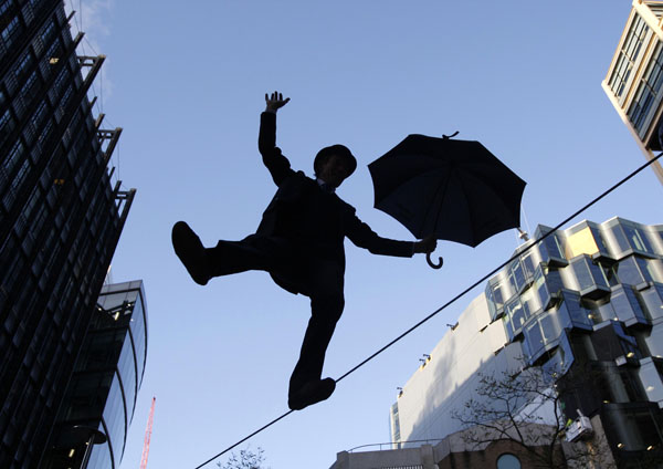 Egy üzletembernek öltözött kötéltáncos egyensúlyoz London üzleti negyedében.