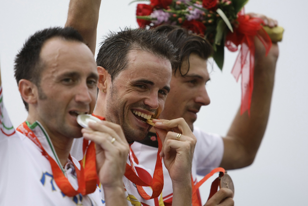 Gold medallist Samuel Sanchez of Spain (C) bites his medal as he stands on the podium with silver medallist Davide Rebellin of Italy (L) and bronze medallist Fabian Cancellara of Switzerland after the men's road cycling competition at the Beijing 200