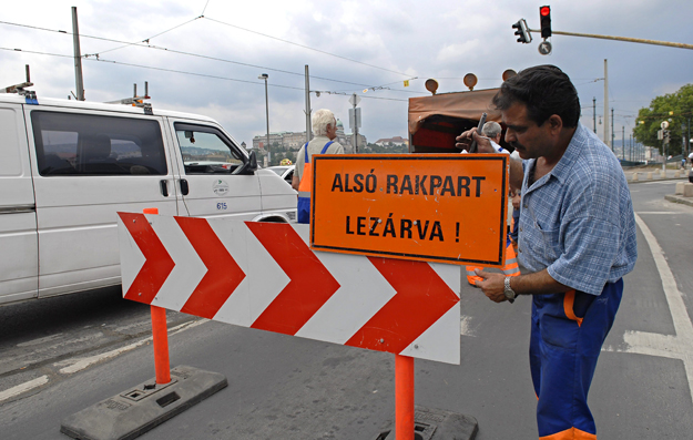 A Fővárosi Közterület-fenntartó munkatársa Alsó rakpart zárva! feliratú táblát helyez el az Erzsébet hídnál, amikor a Duna magas vízállása miatt lezárják a rakpartot