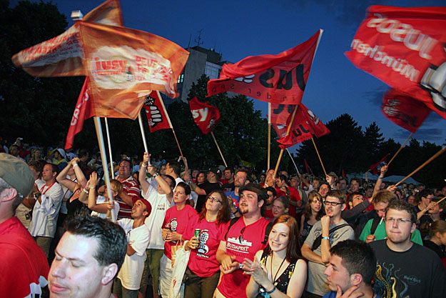 Résztvevők zászlókkal a kezükben állnak a Szocialista Ifjúsági Internacionálé egyhetes világtalálkozójának zárónapi ünnepségen