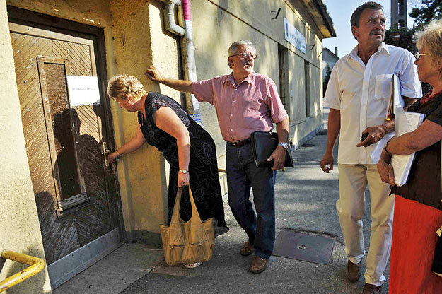 Fót. Testületi ülés. Vargáné dr. Lenkó Erzsébet, jegyző próbálja kinyitni a Városháza ajtaját