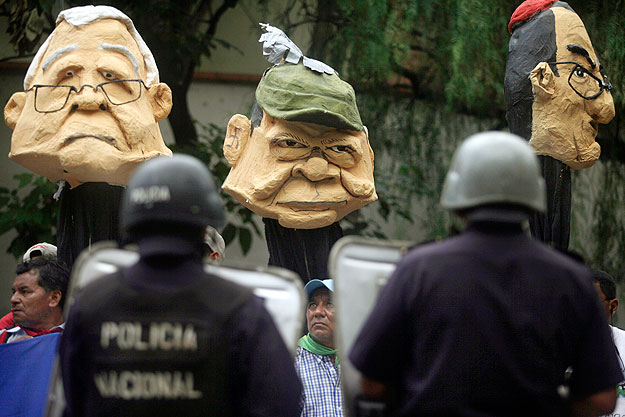 Roberto Micheletti (B) maszkja Zelaya párti tüntető feje fölött