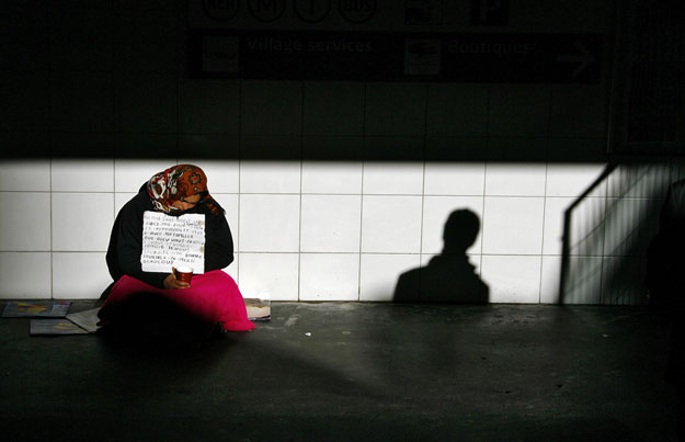 A woman begs at the entrance of an underground train station in Paris