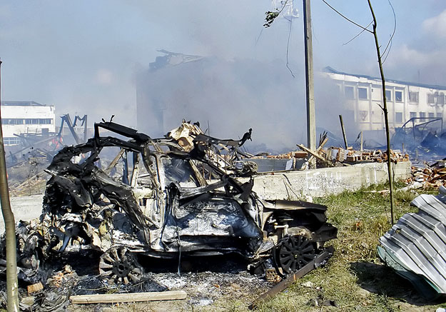 Autóroncs áll üszkös romok között az ingusföldi Nazranyban 2009. augusztus 17-én, miután öngyilkos merénylő robbanószerrel megrakott kisbusszal behajtott a rendőrség udvarára, és felrobbantotta rakományát