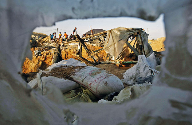 Palesztinok nézik az izraeli légierő által lebombázott egyik titkos alagút romjait a gázai övezetbeli Rafahnál