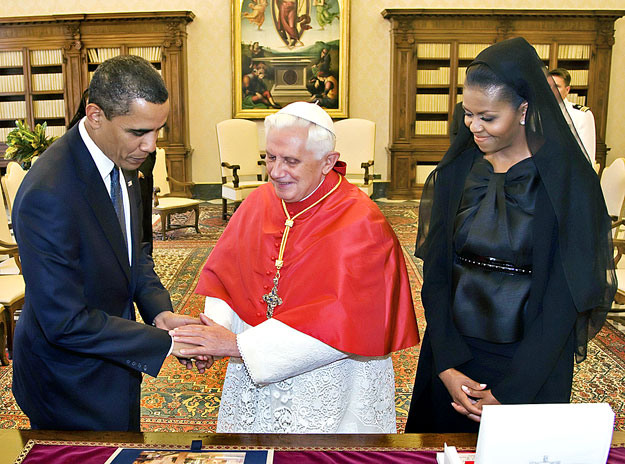Pope Benedict XVI clasps the hands of U.S. President Barack Obama (L) next to first lady Michelle Obama during their meeting in the pontiff's private library at the Vatican July 10, 2009. 