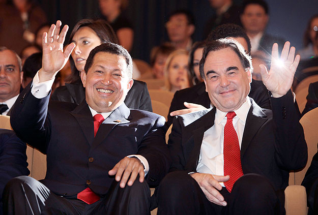 Venezuela's President Hugo Chavez (L) and U.S. director Oliver Stone wave as they sit at the Sala Grande during the 
