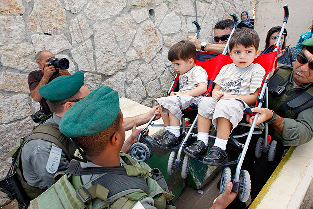 Izraeli biztonságiak két palesztin fiút segítenek át egy biztonsági akadályon a ciszjordániai Betlehemben