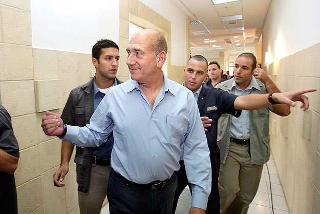 Ehud Olmert volt izraeli kormányfő (k) testőrök kíséretében megérkezik a bírósági tárgyalás helyszínére Jeruzsálemben