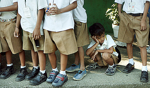 A student sits in line for gifts and food during a Christmas outreach program for public school children at the Department of Education in Manila December 19, 2007. REUTERS/Cheryl Ravelo   (PHILIPPINES)