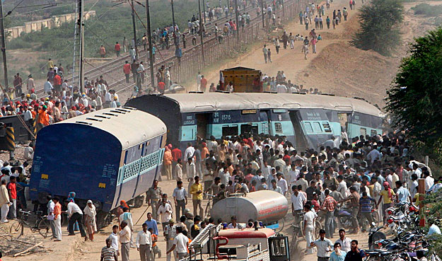 Agra, 2009. október 21.
Kisiklott vasúti kocsik körül állnak emberek Agra közelében 2009. október 21-én, miután összeütközött két személyszállító vonat az észak-indiai városnál. A baleset következtében legalább huszonegy ember életét vesztette, tize