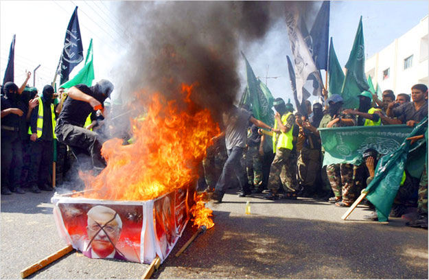 Hamasz-tagok Mahmud Abbasz palesztin államfő fényképeivel borított koporsót égetnek Gázában