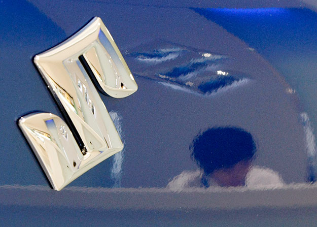 An employee is reflected in a Suzuki Motor's car at a Suzuki Motor showroom in Tokyo June 2, 2009. Bankrupt General Motors Corp said Chinese sales jumped 75 percent in May, but it warned further expansion in Asia-Pacific depended on the region's succ