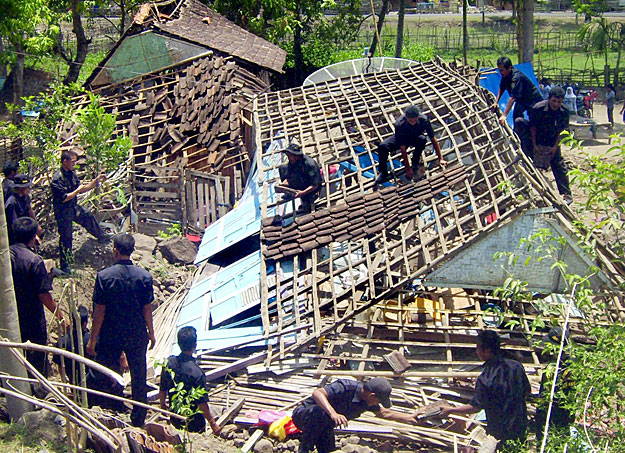 Összedőlt ház romjait takarítják el a mentőalakulat tagjai Bima városában