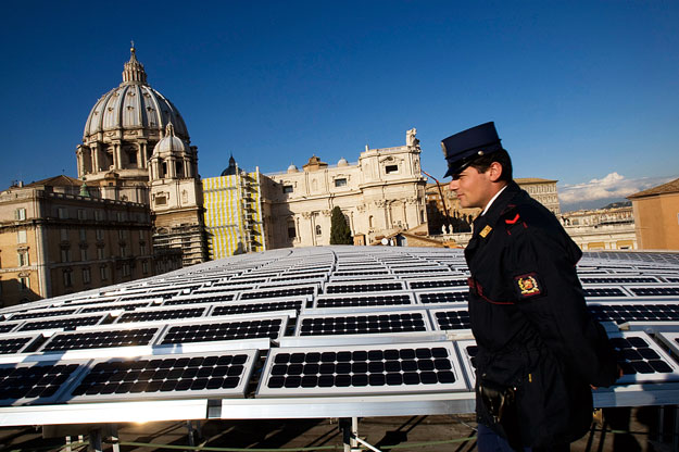 A policeman walks past solar panels covering the roof of the Paul VI hall near the cupola of Saint Peter's Basilica at the Vatican November 26, 2008. The Vatican was set to go green on Wednesday with the activation of a new solar energy system to pow