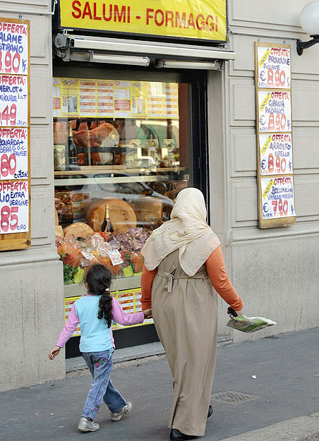 Muszlim nő sétál el egy milánói delikatesz előtt