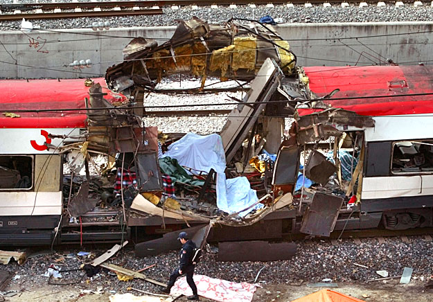 A Spanish policeman walks past a hole blasted through a train in an explosion at Madrid's Atocha train station after an explosion March 11, 2004. Simultaneous explosions killed at least 173 people on packed rush-hour trains in Madrid on Thursday in p