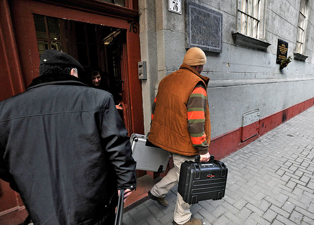 Egy nyomozó táskákkal távozik az Országos Cigány Önkormányzat Dohány utcai székházából