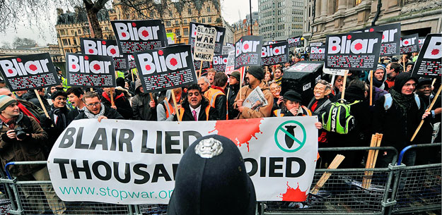 London, 2010. január 29.
Az egykori brit miniszterelnök, Tony Blair maszkját viselő tüntetők fekete koporsót, valamint Bliar feliratú - Blair nevét 