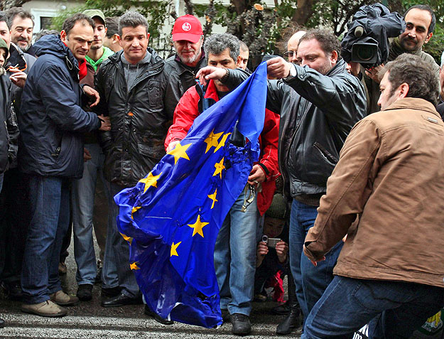 A megszorítások ellen tiltakozó görögök  az Európai Unió zászlaját égetik a EU athéni képviselete előtt