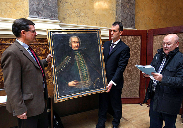 Patay Géza ügyvéd (b) és a családot képviselő Osztroluczky Dénes (k) egy festményt tart kezében Szeyffert Ödön bírósági végrehajtó (j) jelenlétében