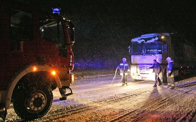 Tűzoltók dolgoznak az éjjeli órákban egy hóban elakadt kamion műszaki mentésén Pogányszentpéter közelében