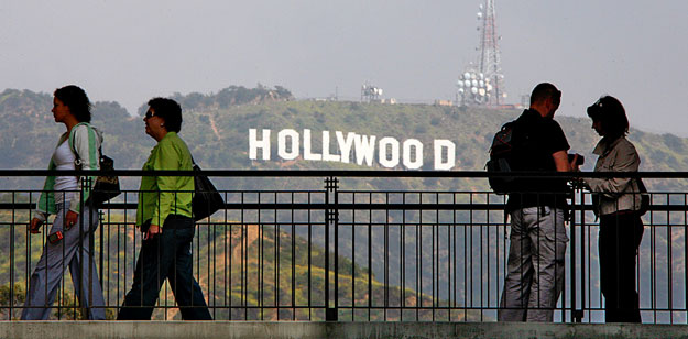 Tourists pause on a walkway at a shopping mall which offers a view of the famed Hollywood sign at the hills in California March 14, 2008.  REUTERS/Fred Prouser         (UNITED STATES