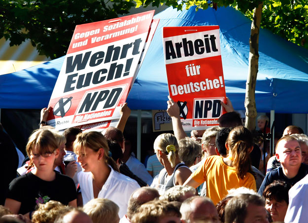 A németországi NPD hívei, „Védjétek meg magatokat!” és „Munkát a németeknek” transzparensekkel