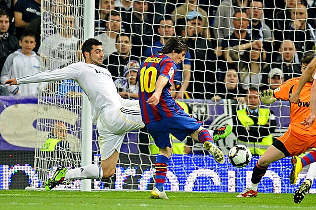 Barcelona's Lionel Messi (C) kicks the ball past Real Madrid's Raul Alibiol (L) and goalkeeper Iker Casillas to score a goal during their Spanish first division soccer match at Santiago Bernabeu stadium in Madrid April 10, 2010. REUTERS/Felix Ordonez