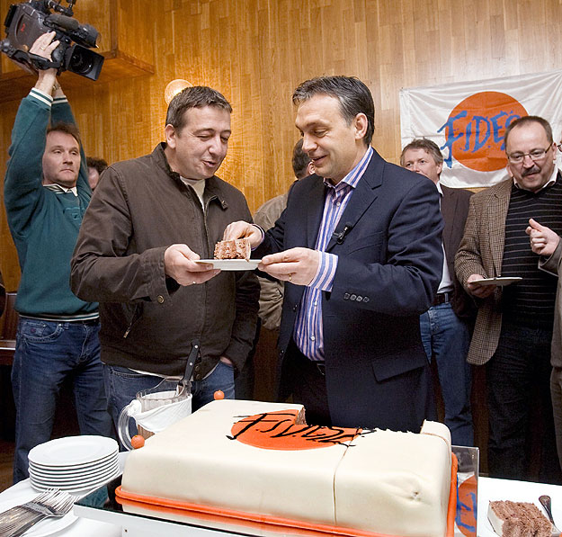 Orbán Viktor a Fidesz elnöke egy szelet tortát tesz Bayer Zsoltnak, a Magyar Hírlap publicistájának tányérjára a párt 21. születésnapi ünnepségén a Bibó István Kollégiumban