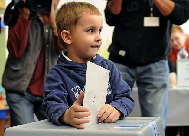 Kisgyerek dobja urnába szülei szavazatát
