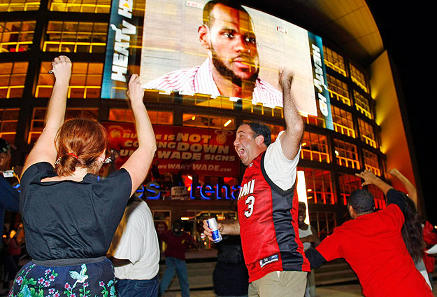 Fans celebrate as a telecast on an electronic screen outside the American Airlines Arena in Miami shows NBA star LeBron James announcing his free agency plans during an interview July 8, 2010. James announced he would be joining free agents Chris Bos