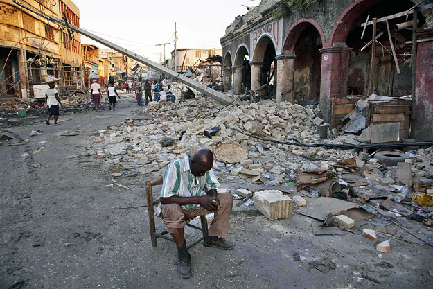 Haiti fővárosában, Port-au-Prince üzleti negyedében, boltja romjai előtt ül egy férfi