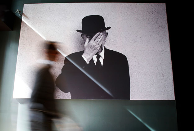 A man walks past a portrait of Belgian artist Rene Magritte ahead of the official opening of the Magritte Museum in Brussels, May 20, 2009.     REUTERS/Francois Lenoir  (BELGIUM SOCIETY)