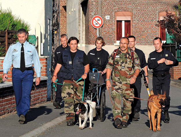 Francia csendőrök kutyákkal vizsgálják át a helyszínt az észak-franciaországi Villers-au-Tertre faluban