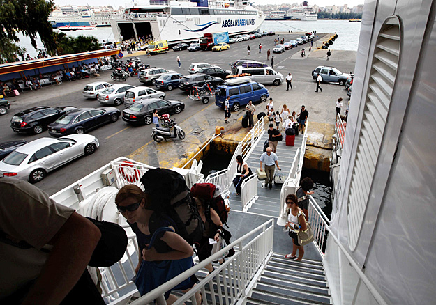 Párosz és Náxosz szigetére induló komphajóra szállnak fel utasok az Athén melletti Pireusz kikötőjében