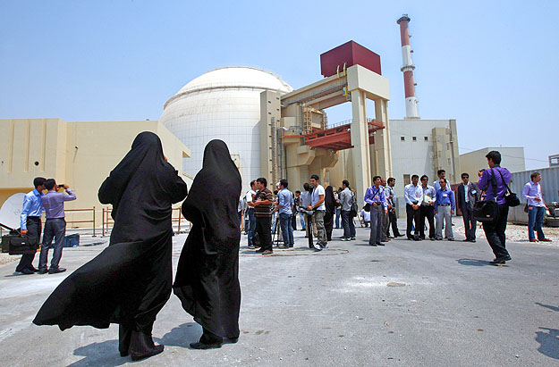 Az atomerőmű biztonsági személyzetének fekete ruhát viselő női tagjai felügyelik a létesítménynél dolgozó újságírókat