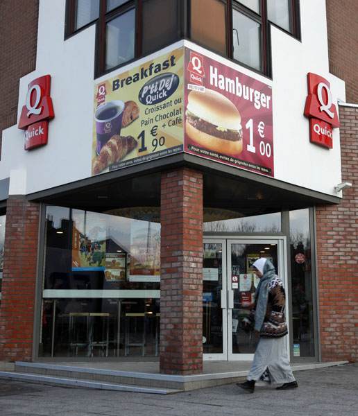 A woman walks past a Quick's restaurant in Roubaix northern France February 18, 2010. A French fast food chain's decision to serve only halal meat in eight restaurants with a strong Muslim clientele has sparked a wave of criticism from politicians de