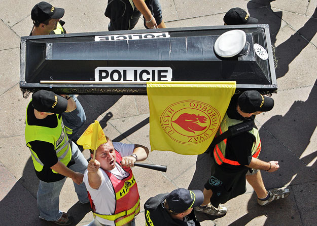 Cseh rendőrök a közszolgálatiság halálát jelképező koporsóval egy szeptemberi megszorításellenes tüntetésen. A szakszervezetek újra az utcára mennek