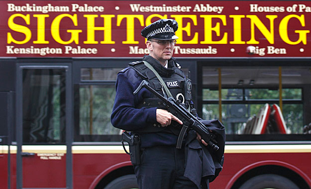 An armed police officer waits to cross the road opposite Downing Street as a tour bus passes behind him, in Westminster, central London, September 29, 2010. Intelligence agencies have disrupted plans for multiple attacks on European cities by a group