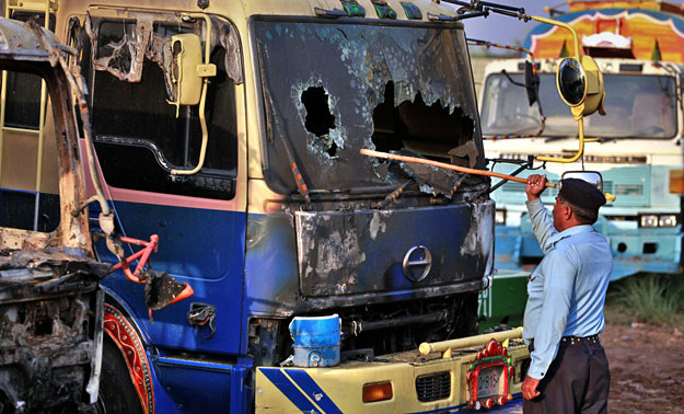 Rendőr egy felgyújtott tartálykocsi mellett Iszlámábádban